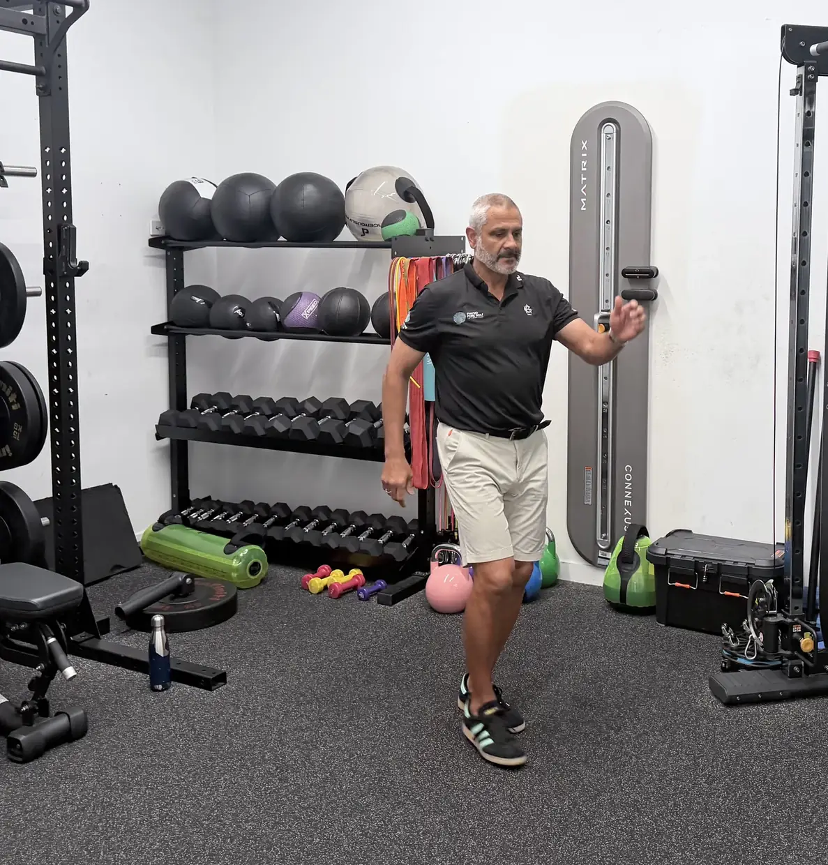 A golf physiotherapist walking on the spot and swinging both arms out to the sides as a warm-up