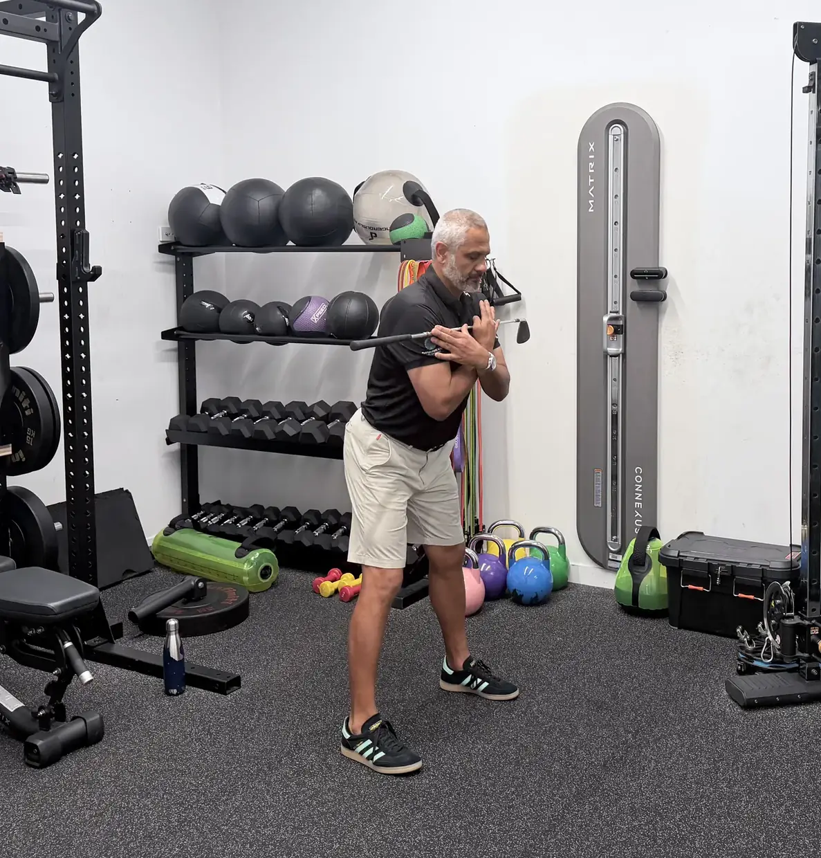 Standing tall with a golf club held across the chest, the start position of a hip hinge