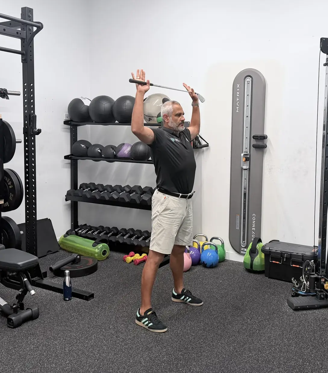 Standing tall with a golf club rotated overhead and behind the head to open the chest