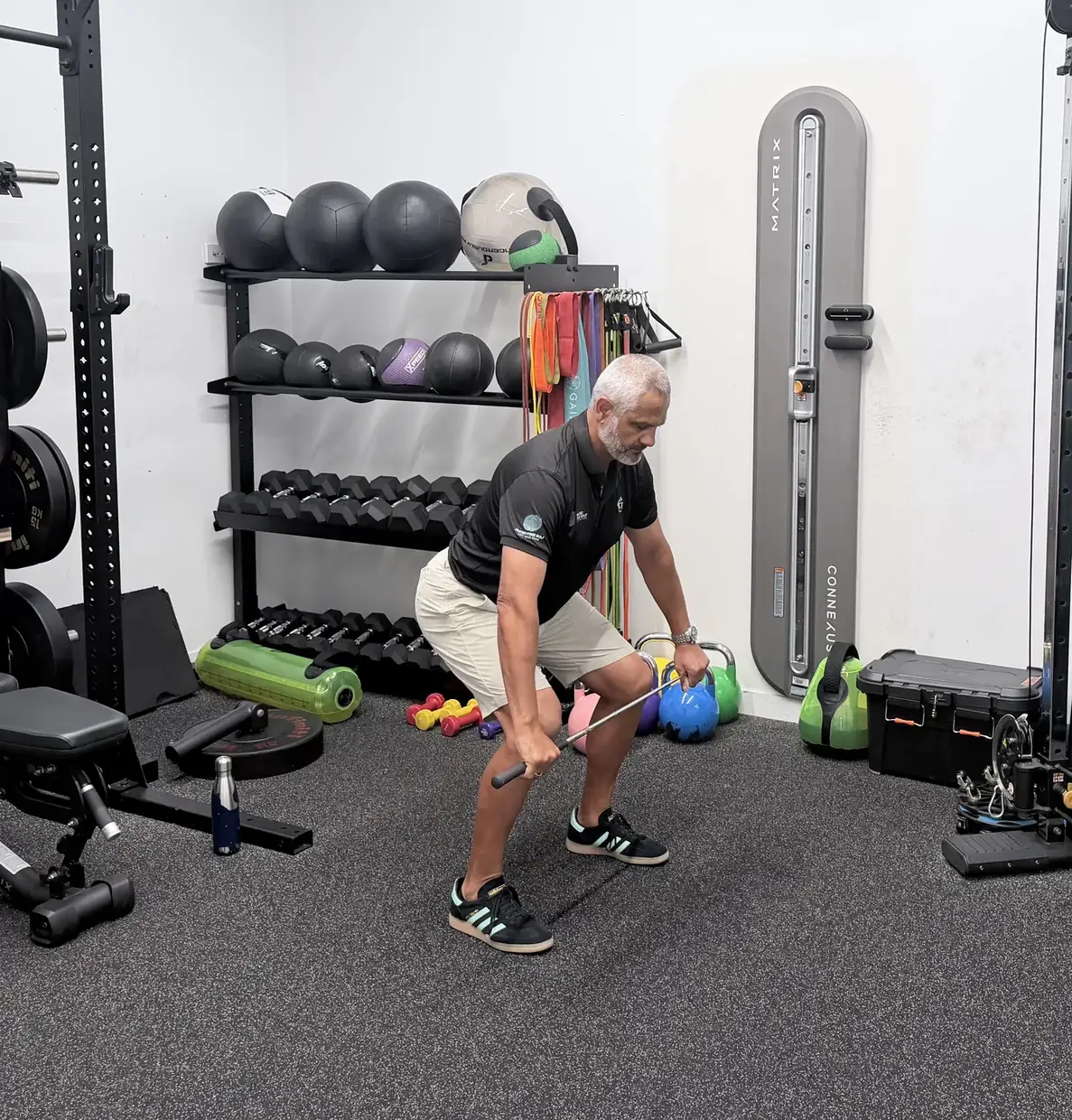 Squatting with the arms relaxed and a golf club held low, the bottom of a squat to reach
