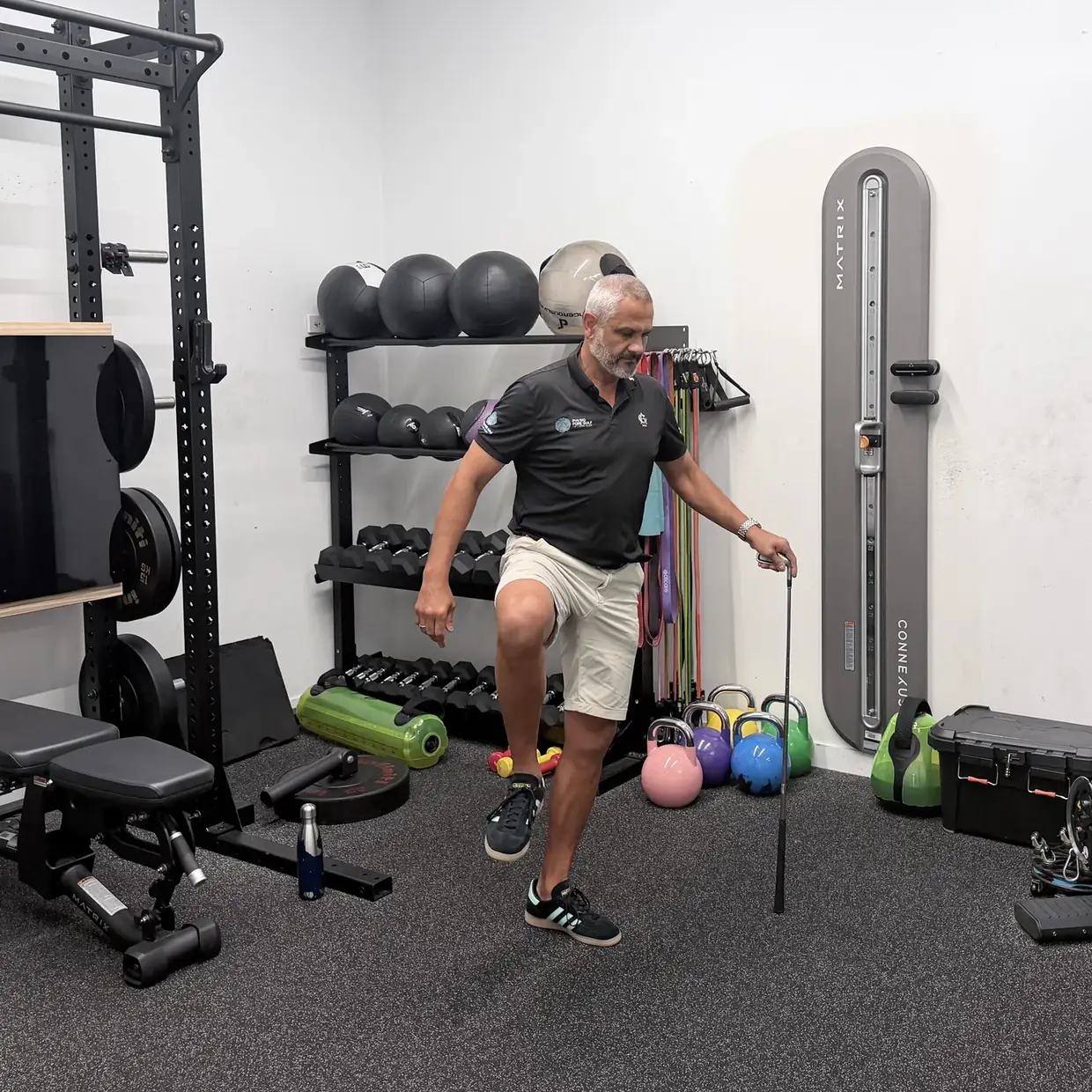 Standing on one leg with the other knee lifted, using a golf club for balance