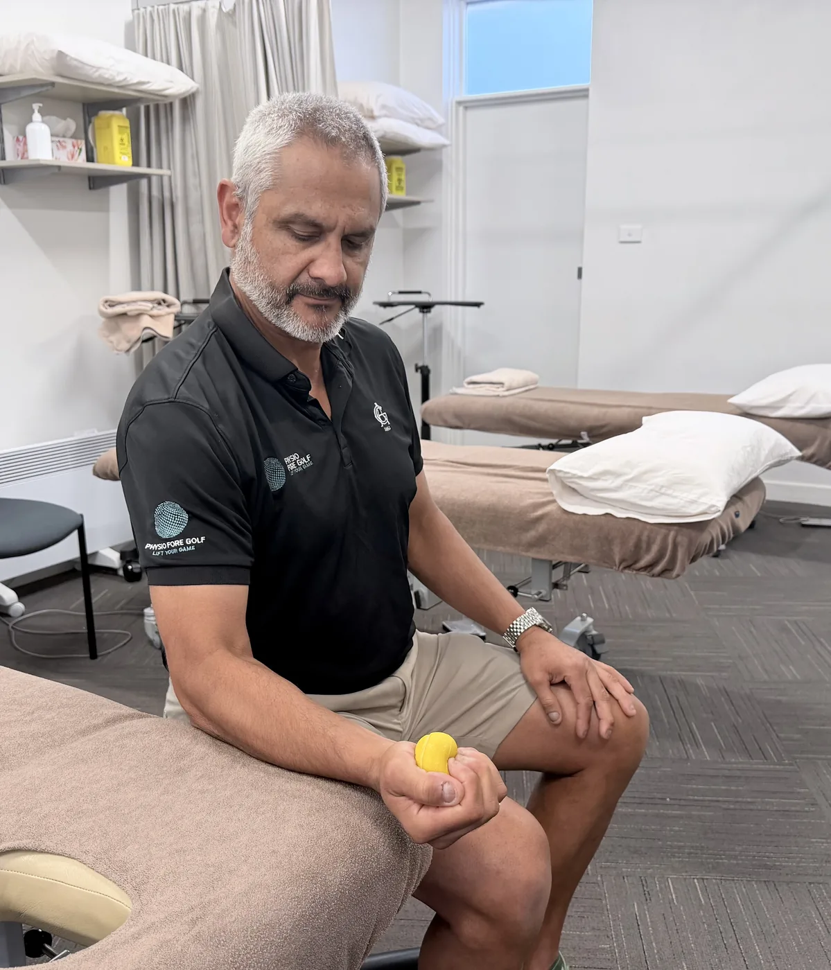A physiotherapist demonstrating grip strengthening with a soft ball held in the hand, the wrist in a comfortable neutral position