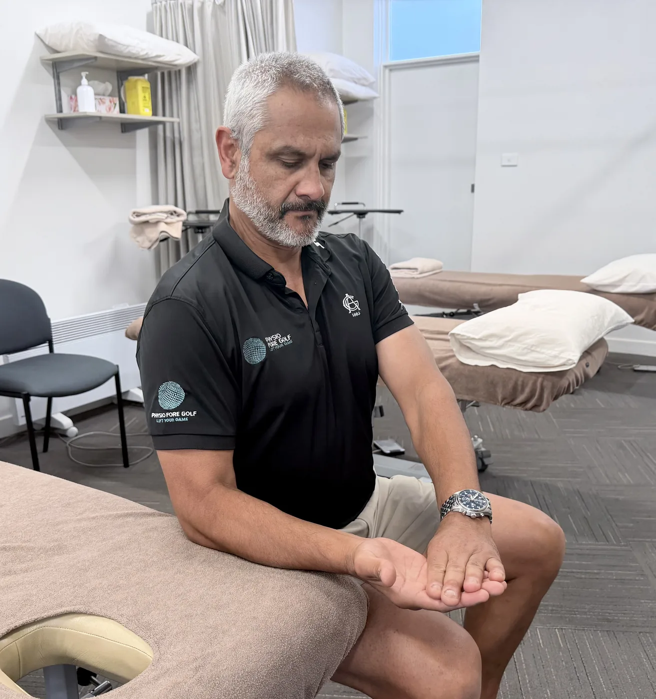A physiotherapist demonstrating isometric wrist flexion, the forearm supported with the opposite hand resisting against the palm