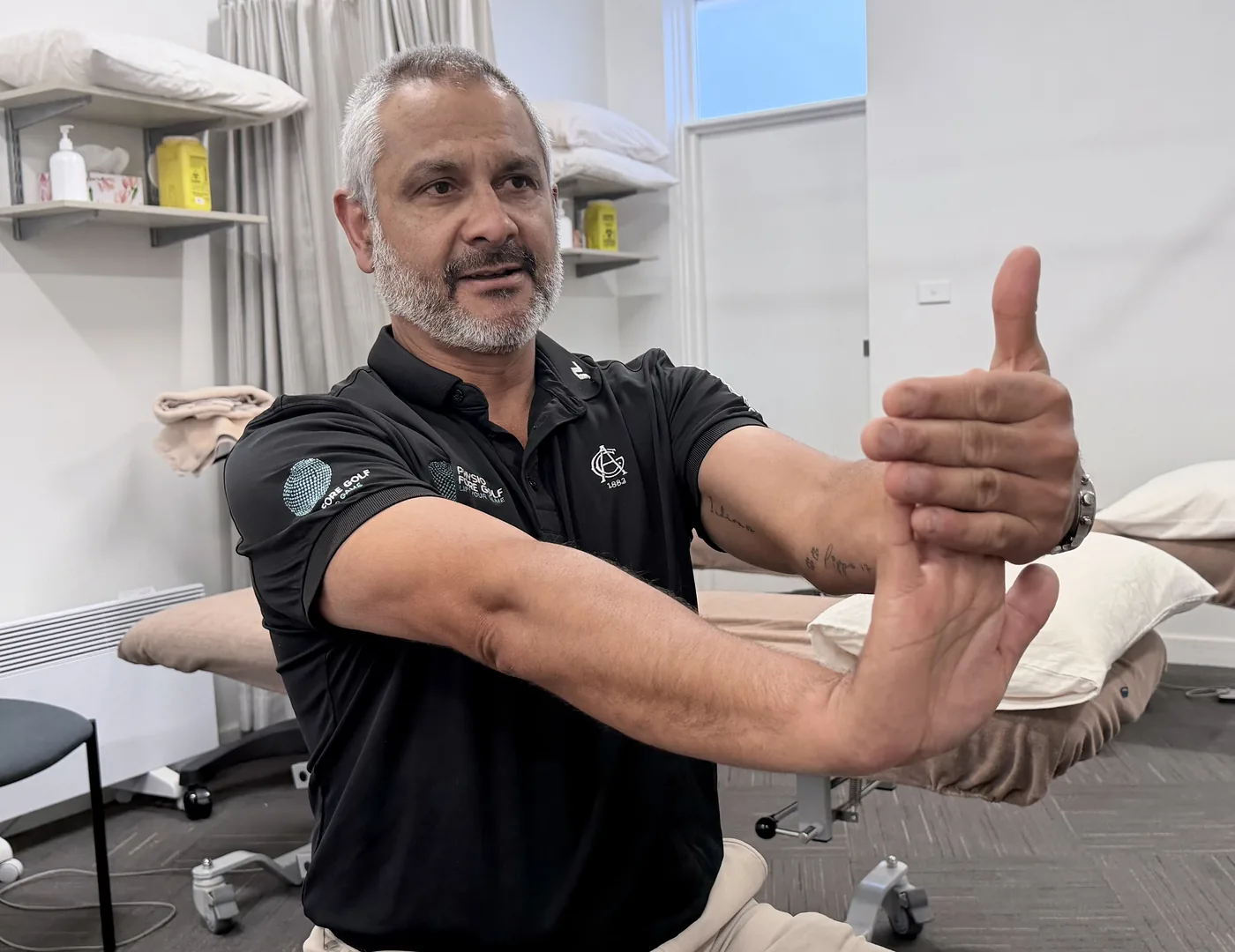 A physiotherapist demonstrating a wrist flexor stretch, arm straight with the palm up and the fingers drawn gently backwards